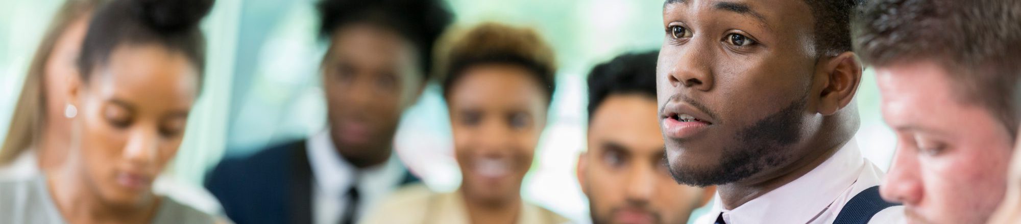 Young male business student poses question during lecture