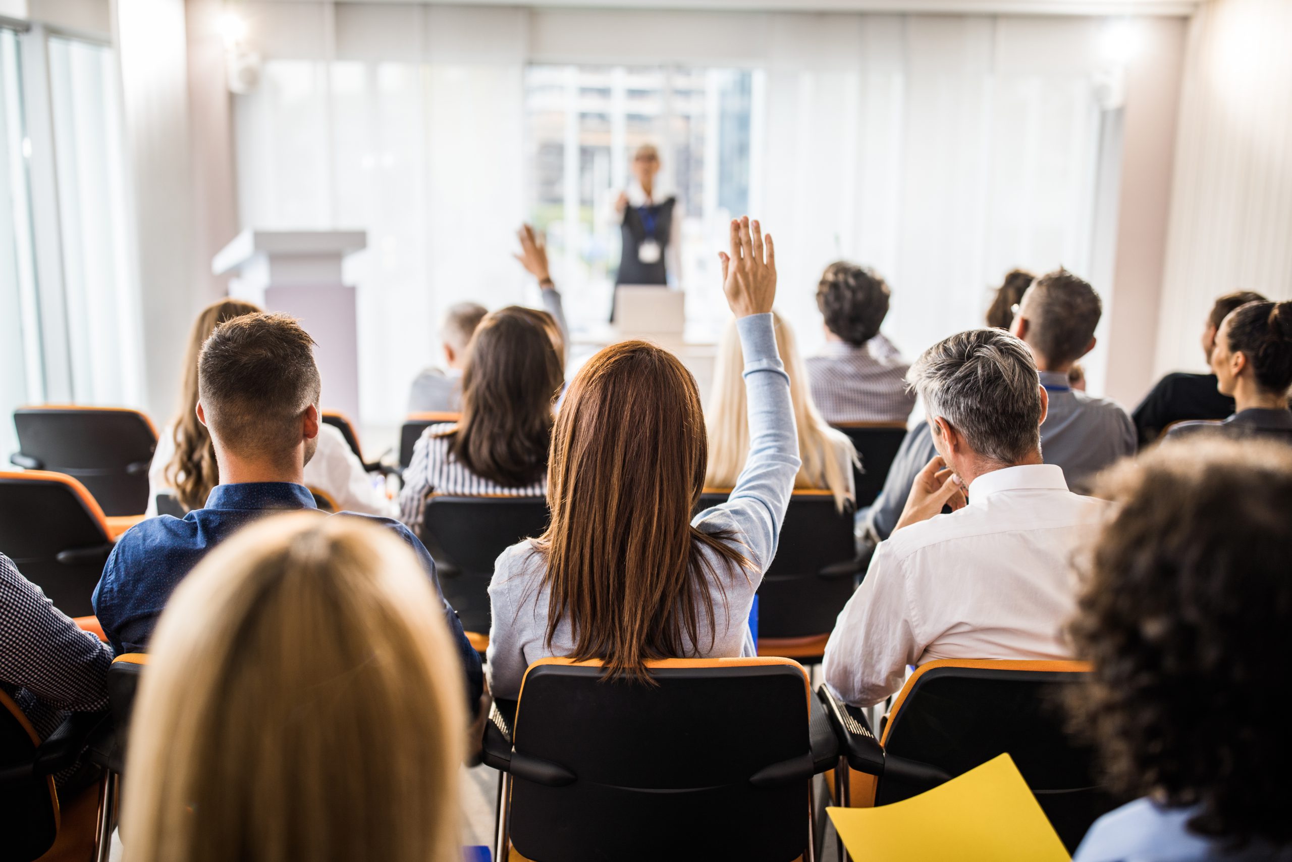 Rear view of large group of business people raising arms on a seminar. Rear view of large group of business people raising arms on a seminar.