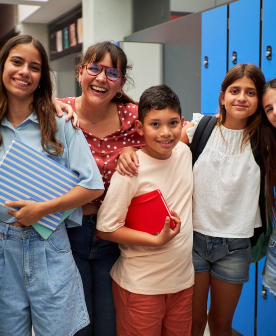Cheerful portrait of a group of preteen student friends with their female teacher at school.