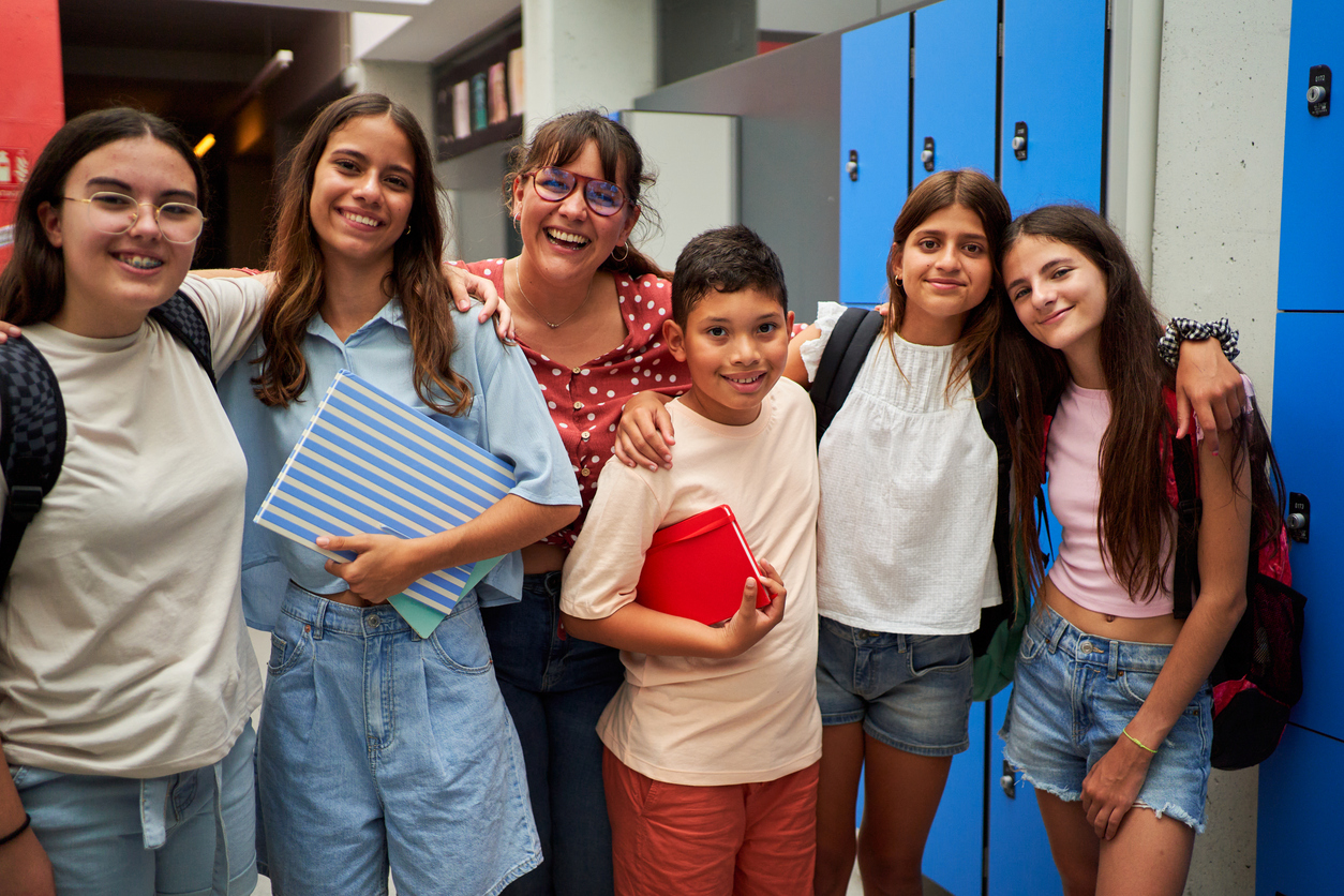 Cheerful portrait of a group of preteen student friends with their female teacher at school.