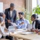 A diverse group of school leaders gathered around a table in thoughtful discussion