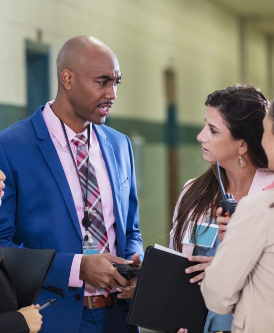 Multiracial teachers having meeting in school corridor