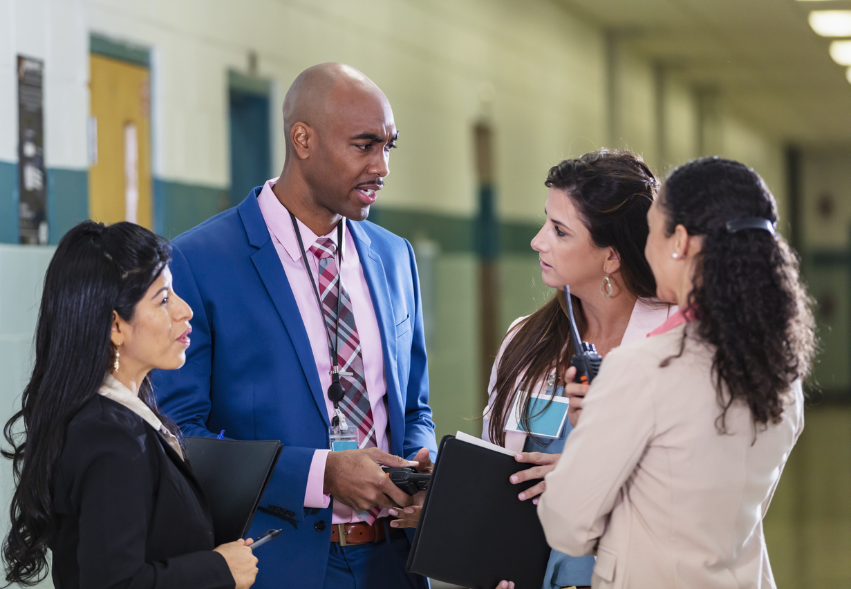 Teachers and school leaders talking together in a school hallway