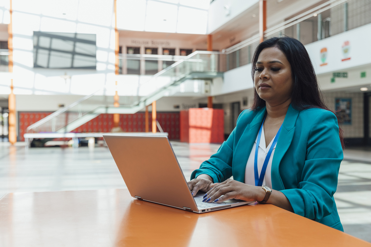 A school principal reviewing work on a laptop in a school office