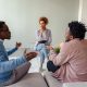 A diverse group of adults in a counseling session led by a mental health counselor