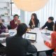A diverse group of education professionals seated around a conference table in focused discussion